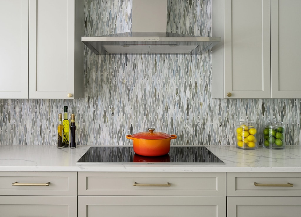 Kitchen cabinet design standards example with shaker cabinets, mosaic backsplash, and stainless range hood