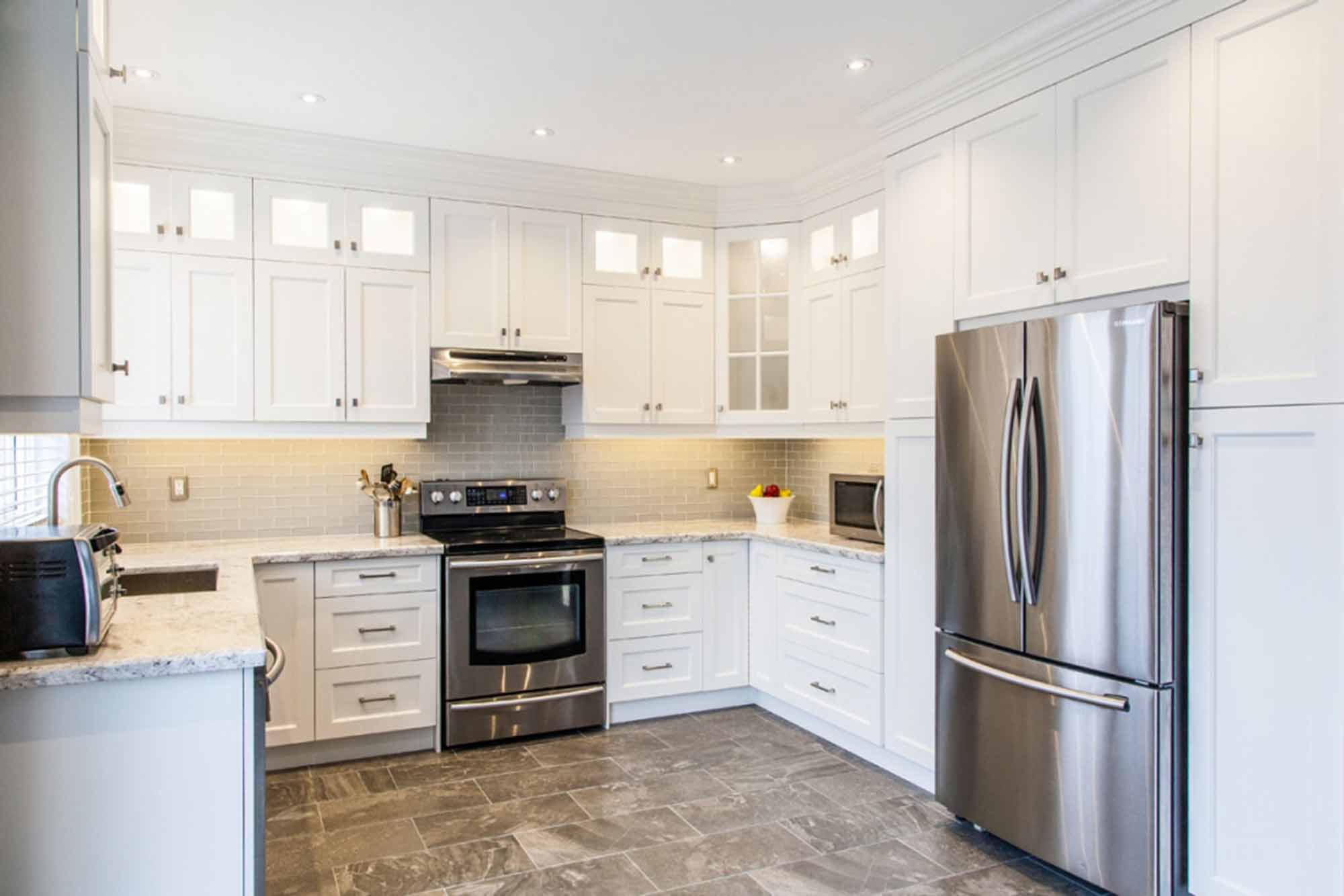 Modern kitchen cabinet Mississauga design with grey shaker cabinets, quartz island, and brass pendant lighting