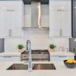 Modern white low price kitchen cabinet design with minimalist doors, quartz countertop, and stainless range hood