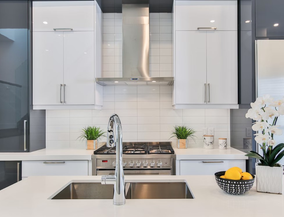 Modern white low price kitchen cabinet design with minimalist doors, quartz countertop, and stainless range hood