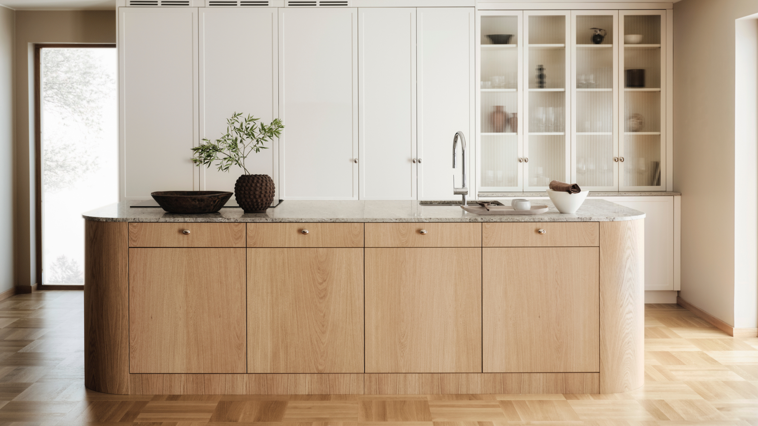 Modern minimalist kitchen by a kitchen cabinet supplier, featuring white built-in cabinets, a natural wood island, and a marble countertop with integrated sink.
