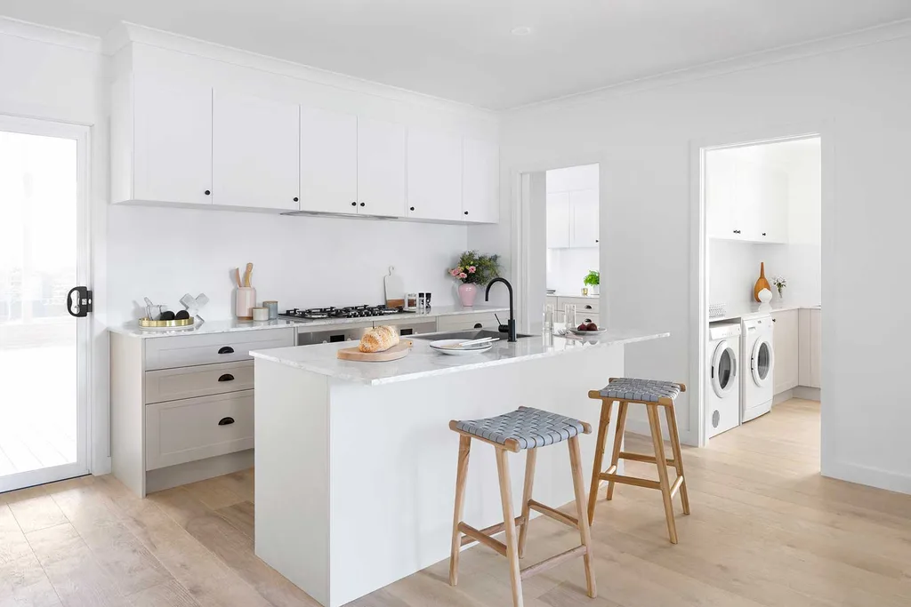 Modern white kitchen cabinets with minimalist design, large island, and quartz countertop in a bright open-plan kitchen