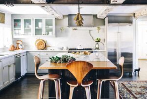 Modern farmhouse kitchen with gray shaker cabinets, marble island, and stainless steel fridge from trusted KITCHEN SUPPLIERS.