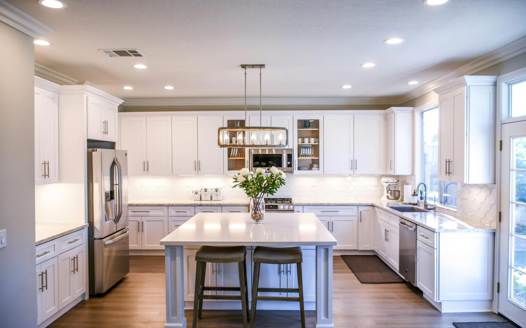 Modern bright kitchen with white shaker premade kitchen cabinet set, large island, stainless steel appliances, and recessed lighting.