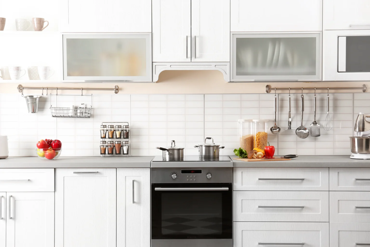 White shaker kitchen cabinets with frosted-glass upper doors and stainless pulls in a modern kitchen.