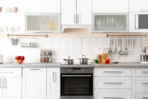 White shaker kitchen cabinets with frosted-glass upper doors and stainless pulls in a modern kitchen.