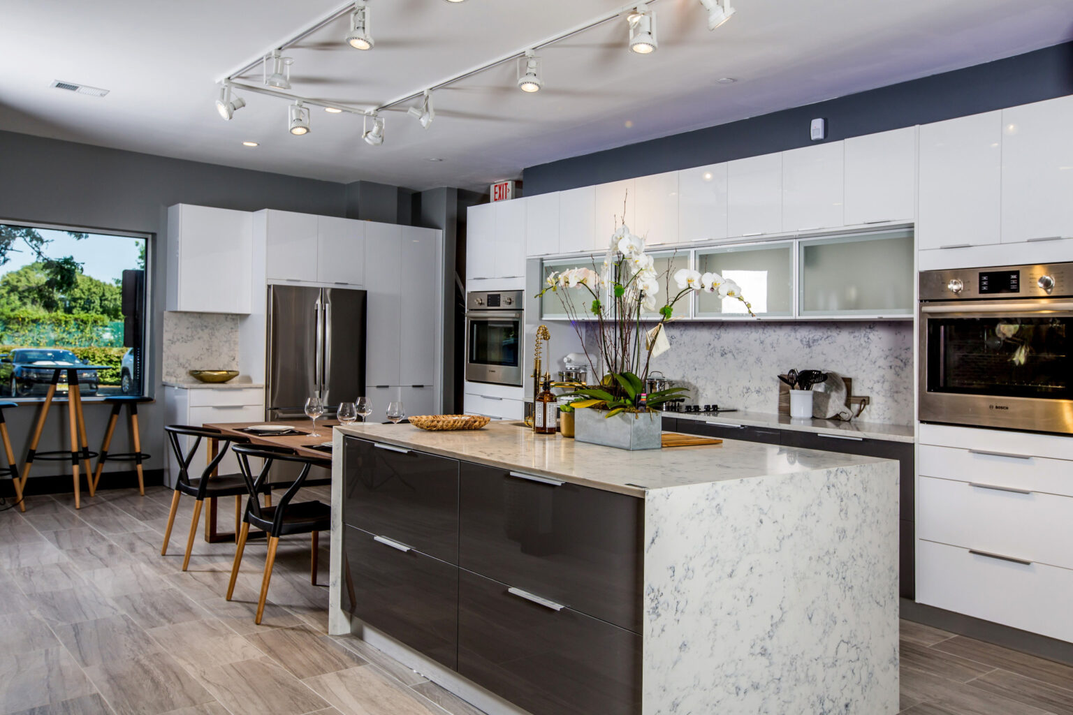 Modern kitchen cabinet Mississauga design featuring a waterfall marble island, dark wood island drawers, and sleek white high-gloss cabinetry in a contemporary Canadian kitchen.