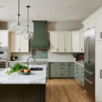 Modern two-tone kitchen cabinets with cream upper cabinets, sage green base cabinets, a quartz island, and stainless steel appliances.