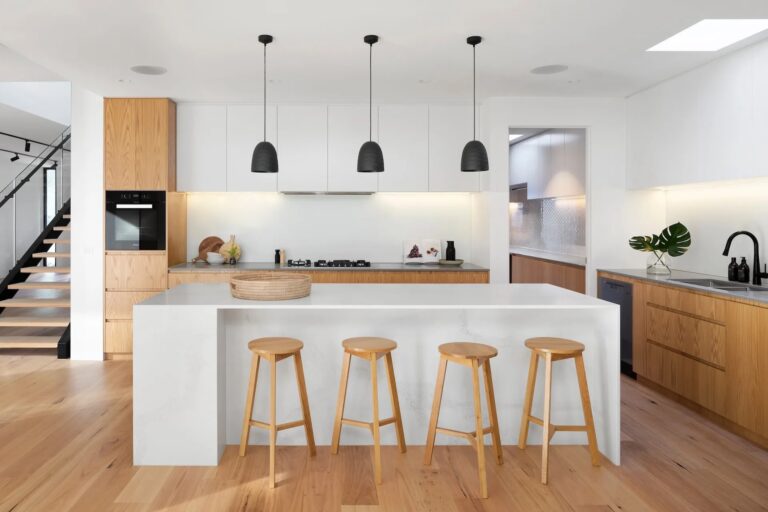 Modern kitchen cabinets in white and natural wood with a large island in a minimalist open-concept kitchen