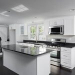 Modern white shaker-style Kitchen Cabinets Vaughan design with black countertops, large island, and stainless steel appliances