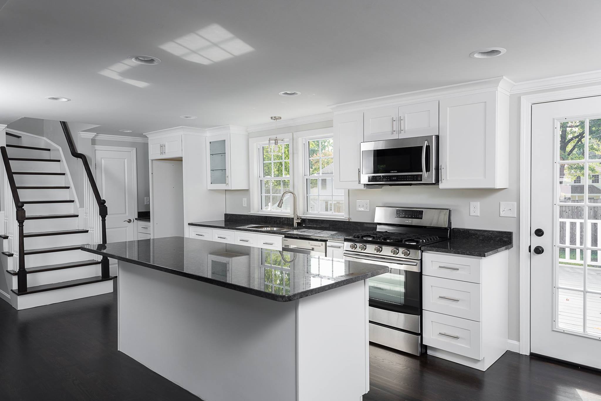 Modern white shaker-style Kitchen Cabinets Vaughan design with black countertops, large island, and stainless steel appliances