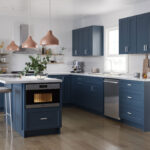 Modern navy shaker kitchen cabinets Mississauga with a waterfall island, white quartz countertops, and warm copper pendant lighting.