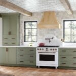 Ready-to-assemble kitchen cabinetry in sage green with shaker cabinets and a natural wood range hood