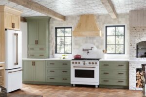 Ready-to-assemble kitchen cabinetry in sage green with shaker cabinets and a natural wood range hood