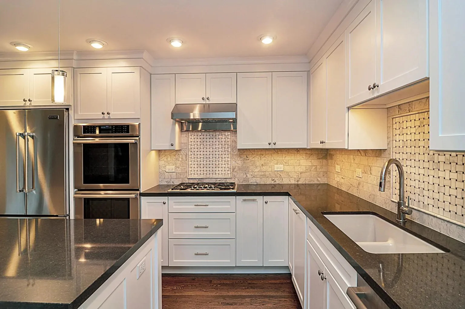 Modern white shaker Kitchen Cabinets Markham with black countertops, stainless steel appliances, recessed lighting, and a bright U-shaped layout.