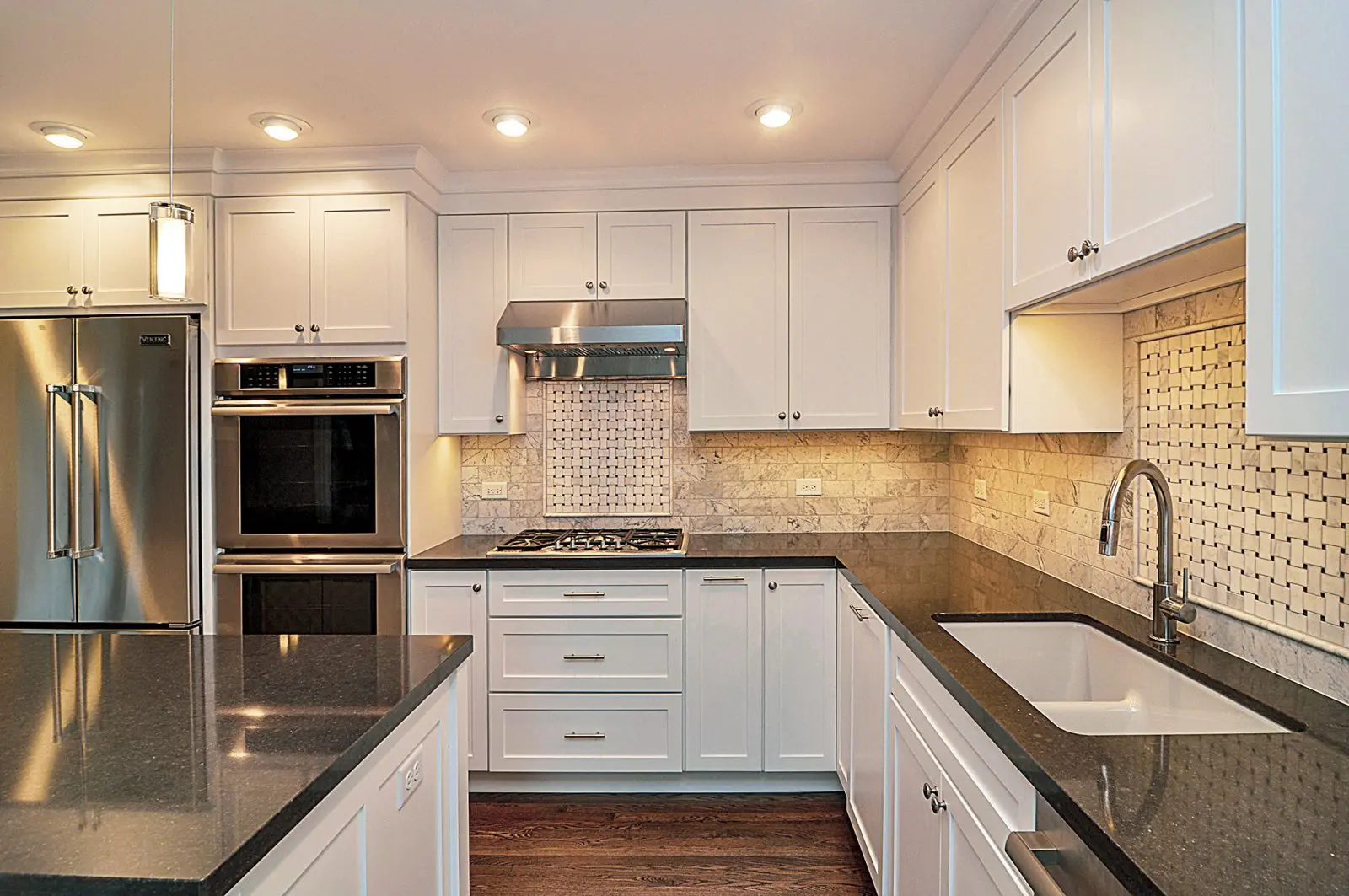 Modern white shaker Kitchen Cabinets Markham with black countertops, stainless steel appliances, recessed lighting, and a bright U-shaped layout.