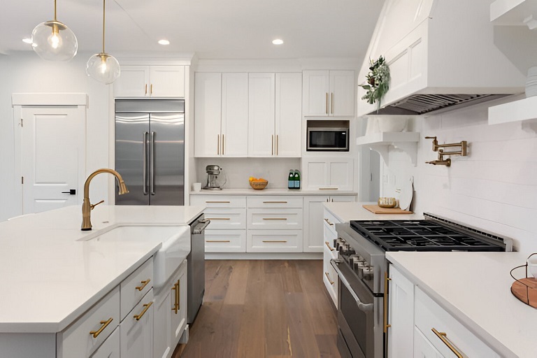 Kitchen Cabinets Markham in a bright modern white kitchen with gold hardware, large island, stainless steel refrigerator, and built-in cabinetry
