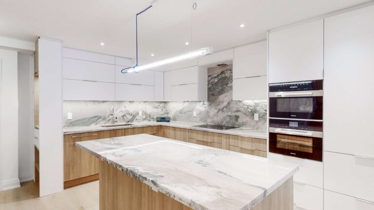 Contemporary Kitchen Cabinets Toronto design with sleek white upper cabinets, warm wood lower cabinets, marble-look countertops, a waterfall island, and built-in wall ovens in a bright modern space.