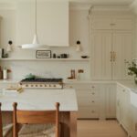 Kitchen Cabinets Milton in a bright modern kitchen with cream shaker cabinets, brass hardware, quartz countertops, and a large island