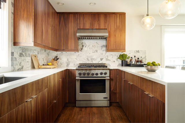 Modern walnut-style Kitchen Cabinets Vaughan design with white quartz countertops, marble backsplash, stainless steel range, and warm pendant lighting.