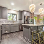 Modern Kitchen Cabinets Vaughan design featuring gray shaker cabinets, a large island with marble-style countertops, pendant lighting, and elegant gold-accent bar stools.