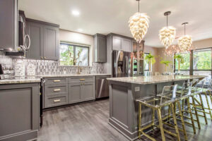 Modern Kitchen Cabinets Vaughan design featuring gray shaker cabinets, a large island with marble-style countertops, pendant lighting, and elegant gold-accent bar stools.