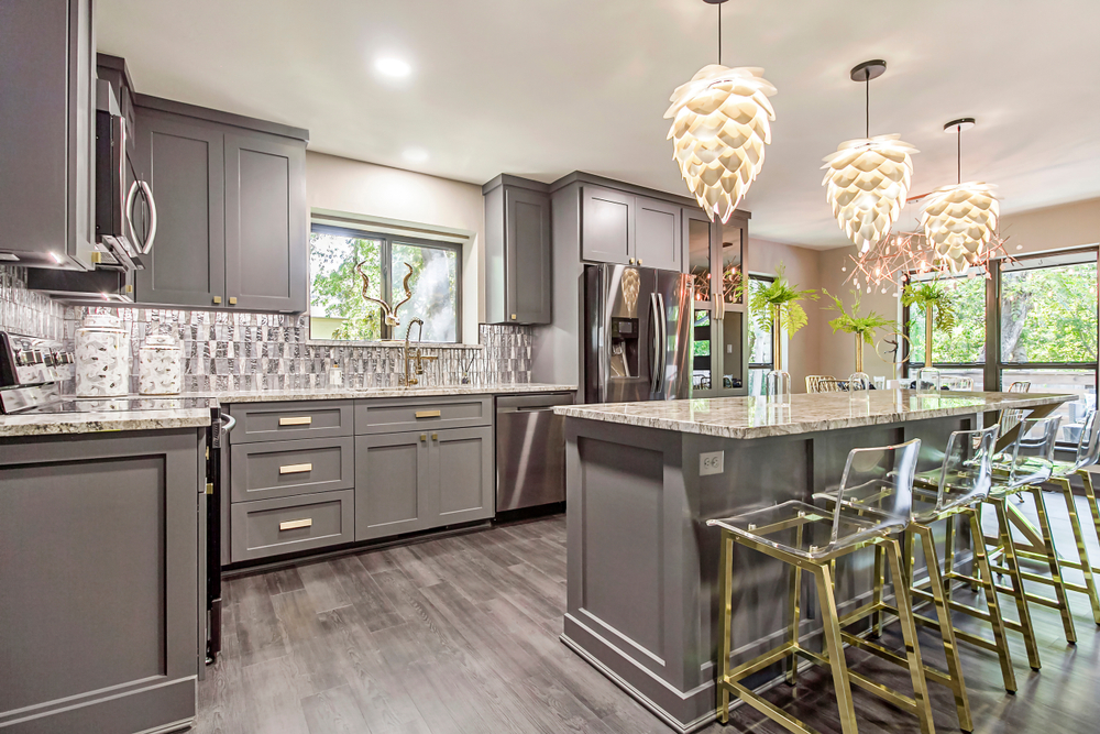 Modern Kitchen Cabinets Vaughan design featuring gray shaker cabinets, a large island with marble-style countertops, pendant lighting, and elegant gold-accent bar stools.