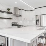 Modern white Kitchen Cabinets Markham design with waterfall island, stainless steel appliances, open floating shelves, and bright luxury interior.