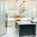 Luxury white kitchen cabinets Mississauga with marble countertops, black island, and modern pendant lighting in an elegant contemporary kitchen.