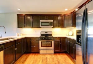 Modern kitchen with dark wood kitchen cabinet doors, stainless steel appliances, and warm lighting in a renovated home.