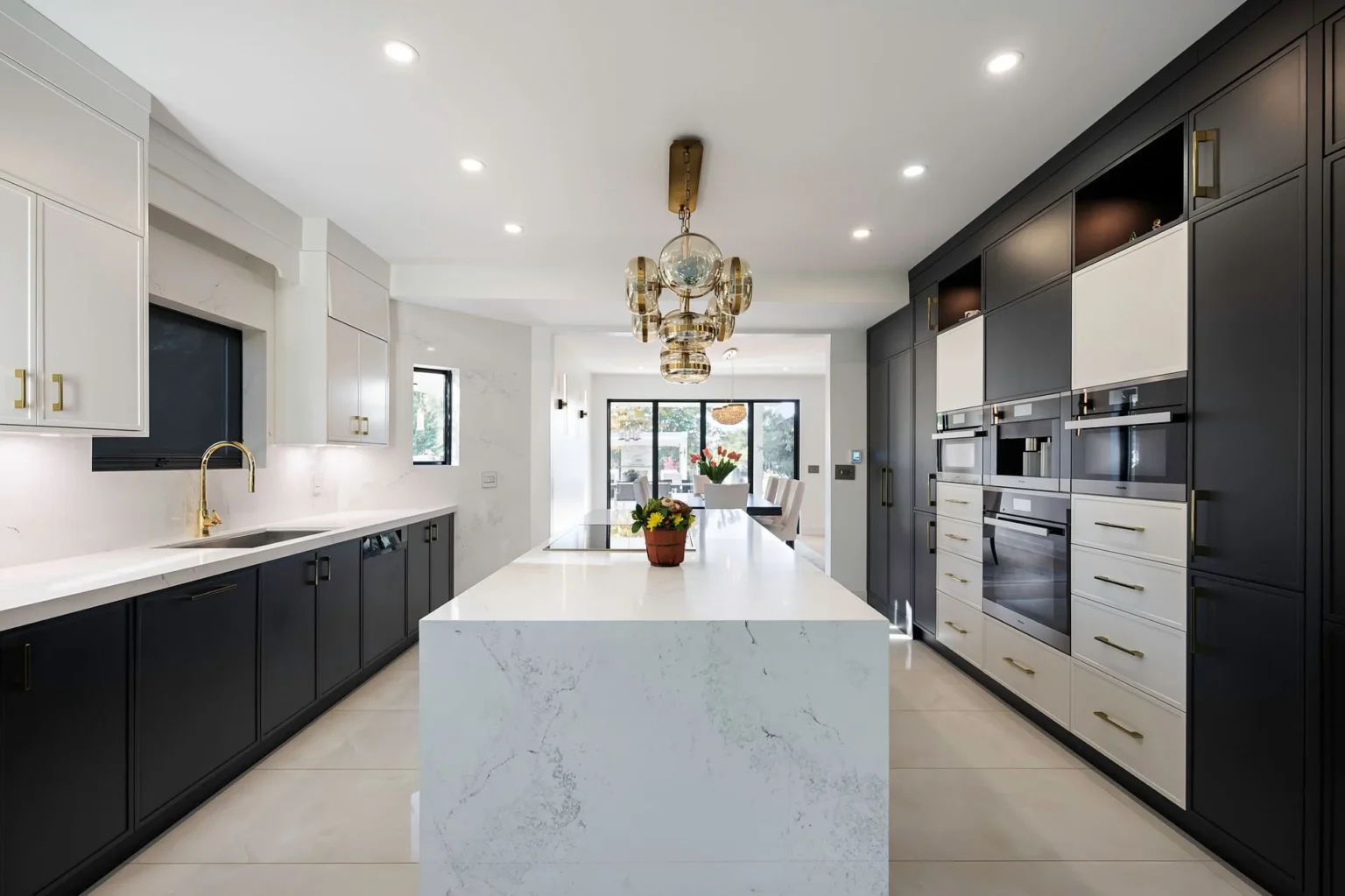 Modern Kitchen Cabinets Brampton design featuring black and white cabinetry, a large waterfall island, and gold hardware in a bright luxury kitchen.
