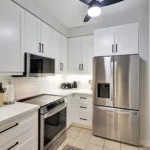 Modern Kitchen Cabinets Oakville design featuring white shaker cabinets, black hardware, quartz countertops, subway tile backsplash, and stainless steel appliances.