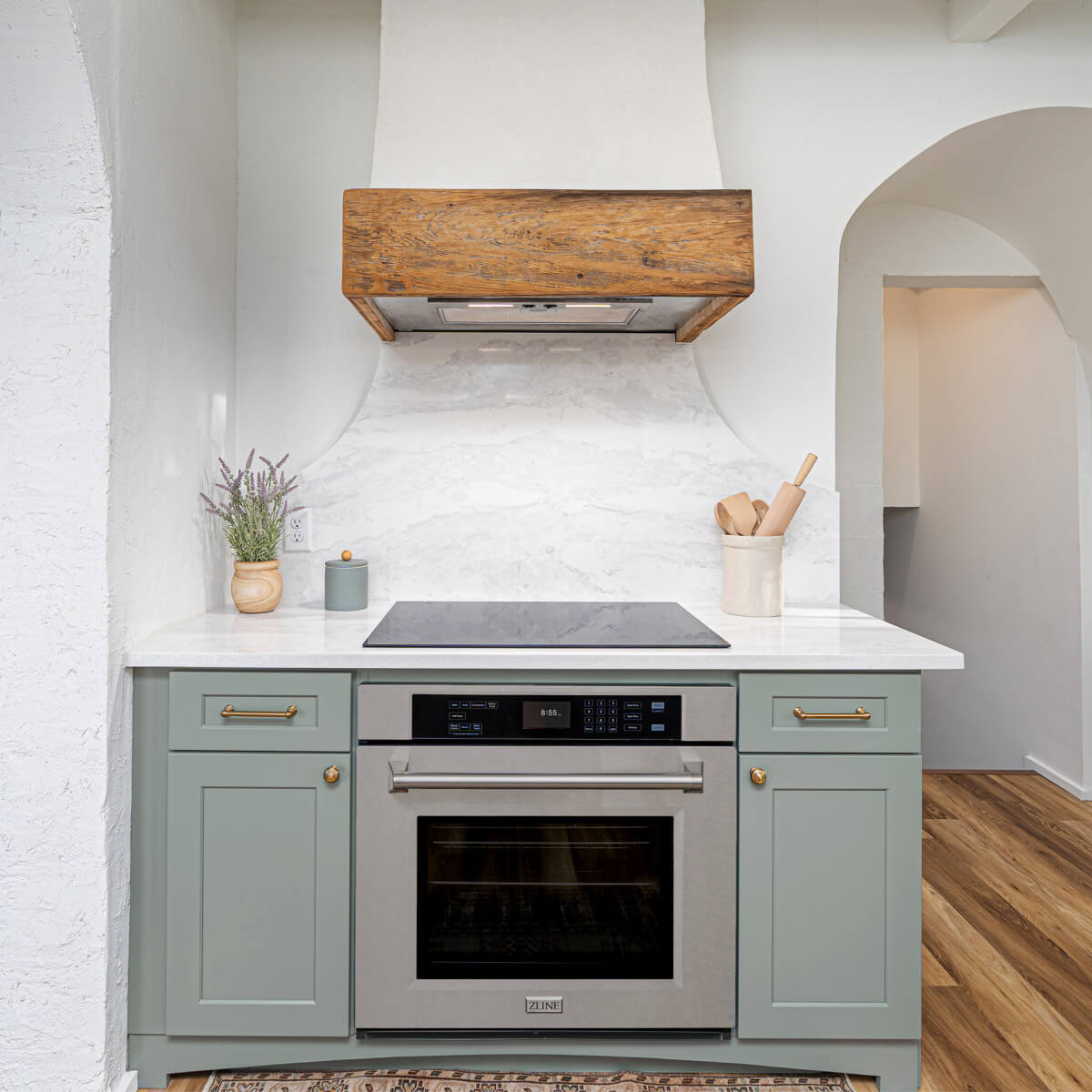 Modern kitchen cabinet with sage green shaker doors and built-in oven under marble countertop