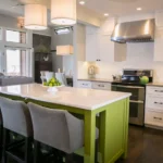 Modern white shaker kitchen cabinets in Mississauga with a bright green island, quartz countertop, and stainless-steel range hood in an open-concept kitchen.