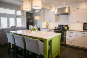 Modern white shaker kitchen cabinets in Mississauga with a bright green island, quartz countertop, and stainless-steel range hood in an open-concept kitchen.
