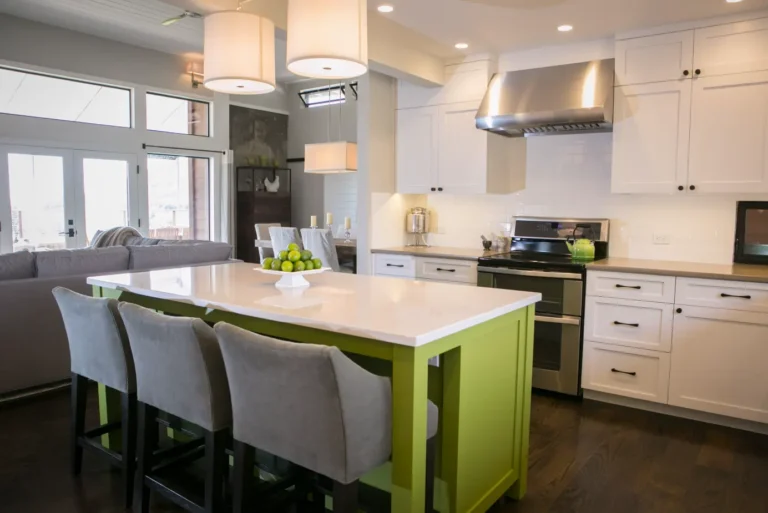 Modern white shaker kitchen cabinets in Mississauga with a bright green island, quartz countertop, and stainless-steel range hood in an open-concept kitchen.