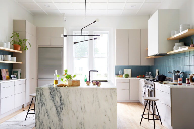 Modern minimalist kitchen featuring IKEA kitchen cabinets with flat-panel fronts, blue tile backsplash, open shelving, and a marble waterfall island.