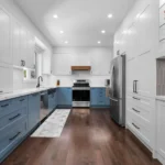 Modern two-tone kitchen cabinets Mississauga renovation featuring white shaker uppers, blue base cabinets, matte black hardware, quartz countertops, and stainless steel appliances.
