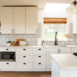Bright modern kitchen cabinets in white shaker style with black hardware, patterned backsplash, and a clean minimalist layout