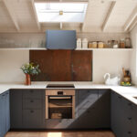 Modern dark gray kitchen design showing IKEA kitchen cabinet colors for small kitchens with white countertops, skylight, and natural light